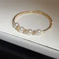 Macro close-up of gold open bangle with white pearls and crystal rhinestone spacers - Style 1