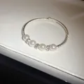 Elegant silver open bangle featuring four pearls and sparkling rhinestone details - Bracelet