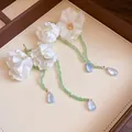 Detail of handmade white fabric flower earrings with green beads and blue teardrop pendants. - Blue Green Beige