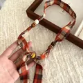 Detailed close-up of a checkered fabric scarf necklace with natural wooden and ceramic beads. - Orange Plaid
