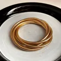 Close-up of multi-layer gold spring bracelets with metallic ribbed texture on a plate. - Gold