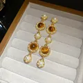 Close-up of elegant French vintage gold drop earrings with pearls and amber stones - Brown