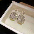 Close-up of 18k gold plated floral cluster ear clips in white jewelry box presentation - Clip-On Earrings / Silver