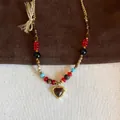 Detail view of a vintage tiger eye beaded necklace featuring a gold heart pendant charm. - Necklace (5#) / Gold-Red
