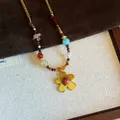Detailed view of a bohemian beaded necklace with golden flower pendant and natural stones. - Necklace (6#) / Gold-Red