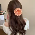 Close-up of a delicate peach fabric flower hair claw clip on long wavy brown hair - Alligator Clip (19) / Orange