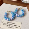 Primer plano de pendientes de aro con cuentas de resina perladas en azul y violeta - Aros de Cuentas / Azul-Rosa
