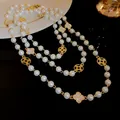 Detailed view of luxury long pearl necklace with sparkling diamond flower accents - Gold