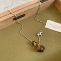 Detailed close-up of tiger eye stone necklace with silver pony charm on green tray - Necklace (48#) / Silver-Coffee