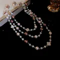 Detailed close-up of a multi-layered pearl necklace featuring rhinestone-encrusted flowers - Off-White