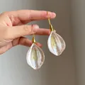 Hand-held detail of elegant petal drop earrings with gold hooks and pearl finish - Petal Drop Style (HE29028) / Gold Pink