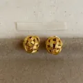 Detailed view of 18k gold-plated woven hollow sphere earrings on a textured background. - Clip-On Earrings / Gold
