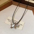 Gros plan détaillé d'un pendentif poney en zircon et d'une perle sur un cordon noir. - Argent