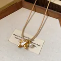 Vue détaillée d'un collier pendentif pégase doré avec accents de perle et de zircon - Or