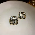 Macro detail of gold-tone square earrings with black zebra pattern and crystals. - Square Enamel Style with Silver Post / Gold