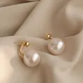 Elegante vergoldete Doppelperlen-Ohrstecker mit minimalistischem Design auf Seidenstoff. - Silbernadel / Gold