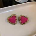 Macro view of pink heart stud earrings with elegant golden chain-link border detail - Fabric Heart