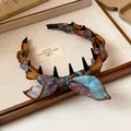 Detailed view of a vintage silk scarf wrapped headband with bow and hair comb teeth - Brown