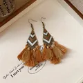 Gros plan détaillé de boucles d'oreilles ethniques à glands sur un plateau rétro - Crochet d'oreille-gland en coquille triangle / Marron
