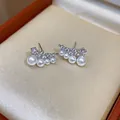 Close-up detail of elegant curved pearl stud earrings with shimmering zircon accents on jewelry box - Silver-White