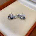 Detailed view of curved stud earrings with grey pearls and sparkling cubic zirconia stones - Silver-Grey