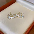Detail view of gold-plated stud earrings with elegant pearls and sparkling zircons - Gold-White
