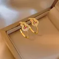 Dettaglio di eleganti orecchini a cerchio dorati a forma di zucca con cristalli rossi e bianchi - 21# Ago D'argento - Oro - Zucca