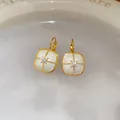 Dettagliato primo piano di eleganti orecchini in smalto quadrato dorato con stella di cristallo - Stile Chiusura a Scatto / Oro-Quadrato