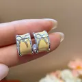 Close-up detail of yellow enamel C-shaped stud earrings with a delicate silver bow. - Bow C-Shape Style / Yellow