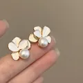 Close-up of 18k gold plated flower pearl stud earrings featuring white enamel petals - Clip-On Earrings / Gold-White