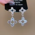 Close-up of silver-tone guilloche textured quatrefoil dangle earrings on display card - Silver