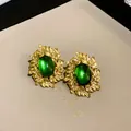 Macro detail shot of elegant vintage gold leaf earrings featuring oval green cat-eye stones - Green