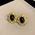 Close-up of vintage gold leaf earrings featuring a polished black oval center stone. - Black