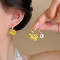 Dettaglio di orecchini eleganti a grappolo di fiori gialli e perle indossati - Yellow Geometric Flower Pearl Drop Style / Giallo