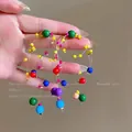 Dettaglio di orecchini colorati con nappe in perle di resina e fili sottili trasparenti - Multicolor Resin Bead Long Tassel Streamline Style / Colorato