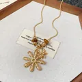 Detailed close-up of gold flower pendant necklace featuring natural tiger's eye beads - Double Flower Pendant Style / Gold