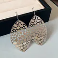 Macro shot of elegant silver hollow-out leaf-shaped earrings on a jewelry display tray. - Hook Style / Silver