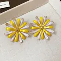 Macro view of elegant yellow and white enamel daisy stud earrings with golden center - Enamel Flower Style / Yellow
