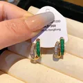Close-up view of geometric gold-plated earrings featuring vibrant green enamel inlay - Geometric Studs / Green