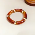 Primer plano de una pulsera vintage de acrílico jaspeado ámbar con separadores de metal dorado - Café Oscuro