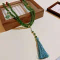 Detailansicht einer langen grünen Perlenkette mit blaugrüner Quaste auf Holzbox - Grüner Perlen-Quasten-Stil / 8mm Perlendurchmesser / Grün