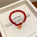 Detailed macro view of a red agate beaded bracelet with a gold rocking horse charm in a box - Success Rocking Horse (HB4808)