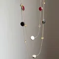 Detailansicht einer zweilagigen Halskette mit roten, schwarzen und weißen Emaille-Anhängern - Gold