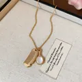Dettaglio di una delicata collana dorata con ciondoli a pettine e specchio in scatola - Pendente Pettine e Specchio / Oro