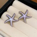 Close-up view of elegant lavender enamel starfish stud earrings in a velvet jewelry box - Purple