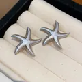 Detail view of silver-toned starfish stud earrings with enamel finish on velvet tray - Gray
