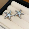 Close-up detail of starfish stud earrings with light blue enamel finish - Blue