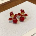Detailed macro of red enamel flower stud earrings featuring elegant hanging beads - Flower Pendant Style