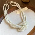 Triple-strand knotted cream pearl necklace displayed elegantly on a wooden tray - Triple Layer Knot Pearl Necklace / White
