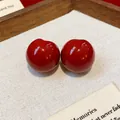 Close-up of gloss red resin stud earrings on a minimalist linen display - Round Ball Style